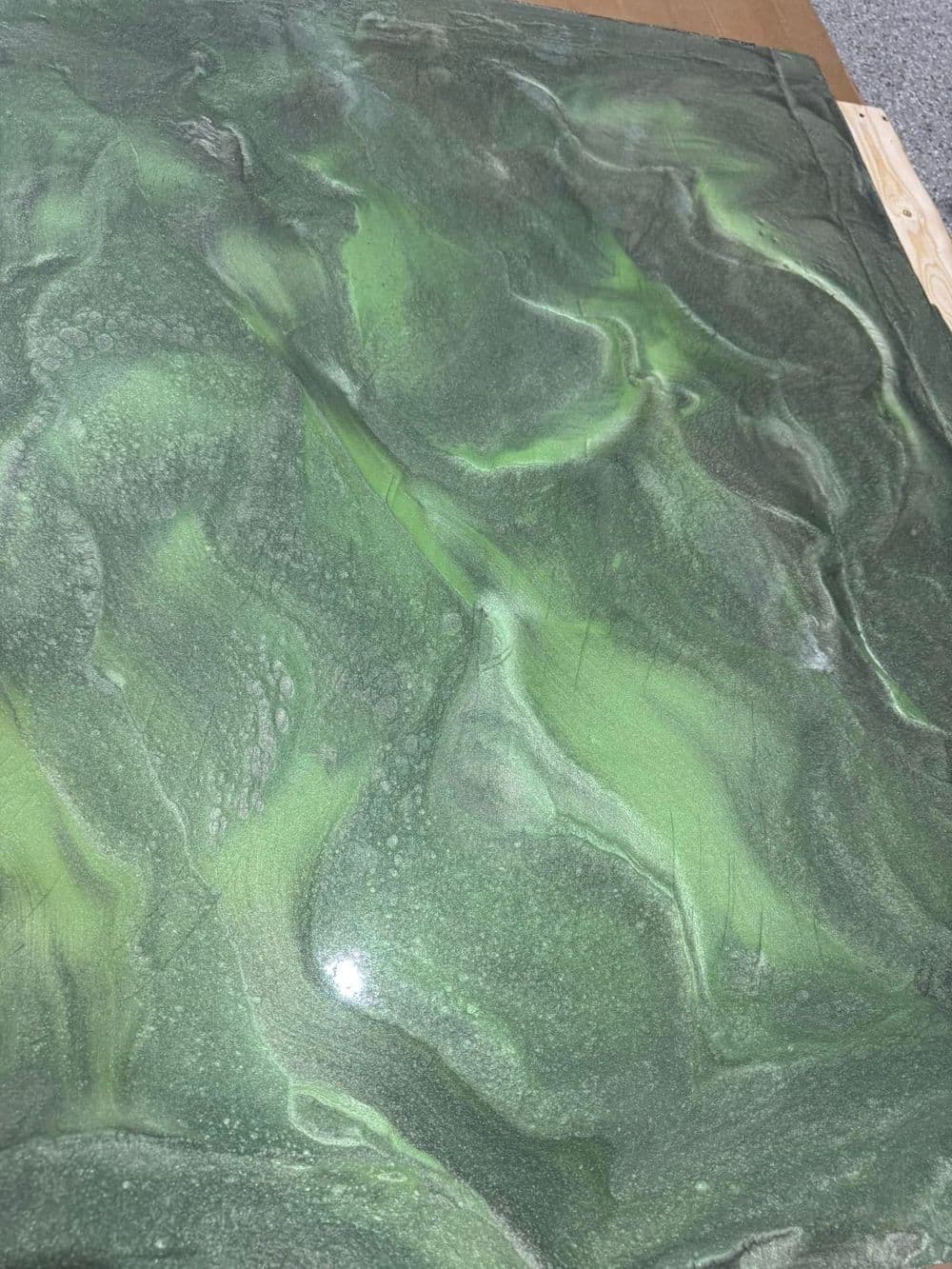 Abstract green textured surface with shimmering details resembling waves or flowing water.