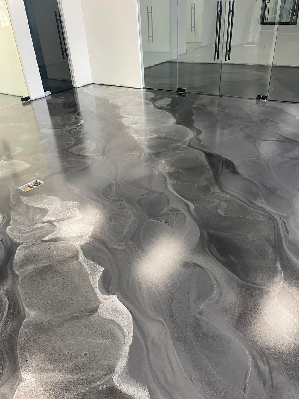 Modern polished epoxy floor with gray swirls in an open, bright interior space.