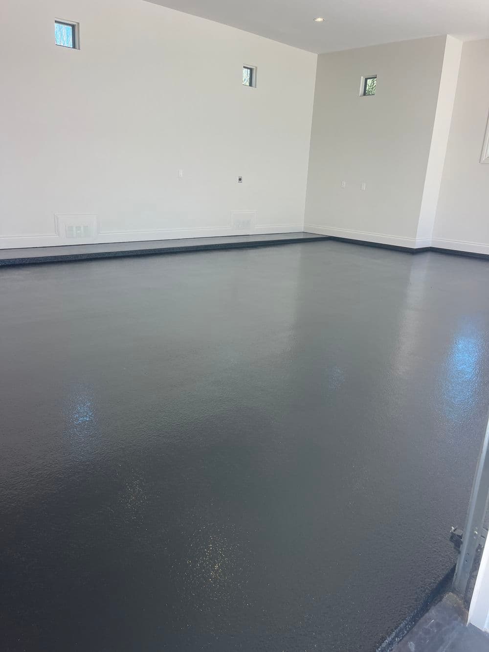 Newly poured gray epoxy floor in a bright, open room with natural light.